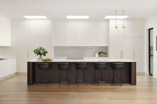 A kitchen with white cabinets and a dark wood island