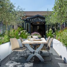 Small urban garden with outdoor dining table and chairs showing creative container planting in a small space