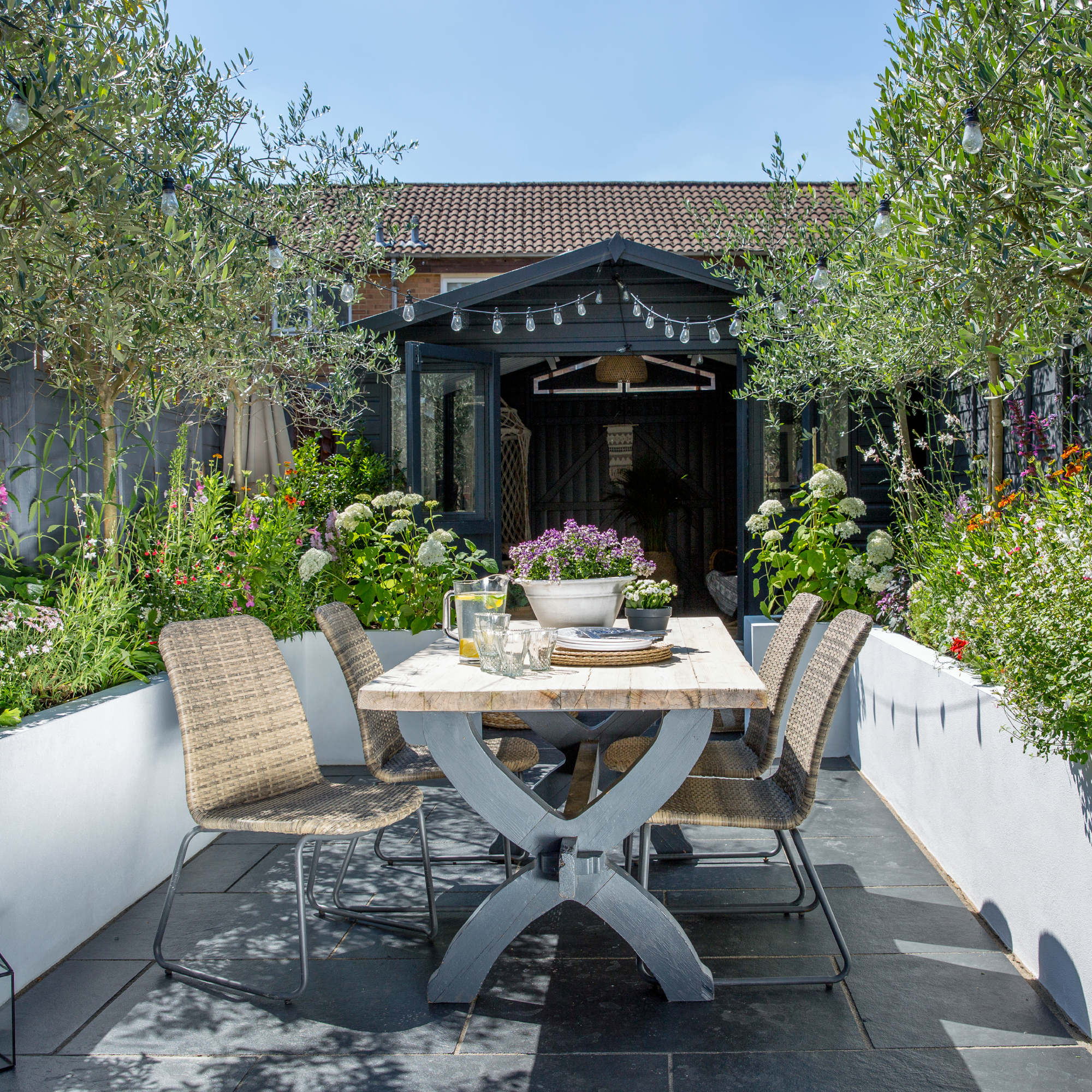 Small urban garden with outdoor dining table and chairs showing creative container planting in a small space