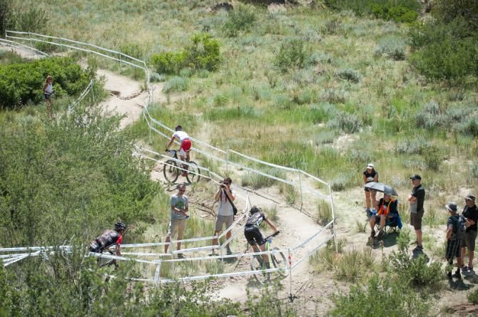 Riders make their way down a technical descent while spectators look on during the elite men's race.