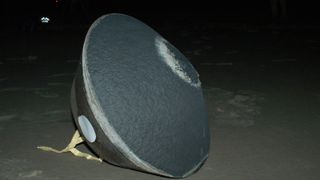 A medium-sized gray container in the shape of a top on the ground.