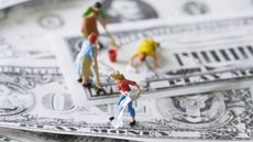 Small figurines representing cleaning people work on cleaning fake money.