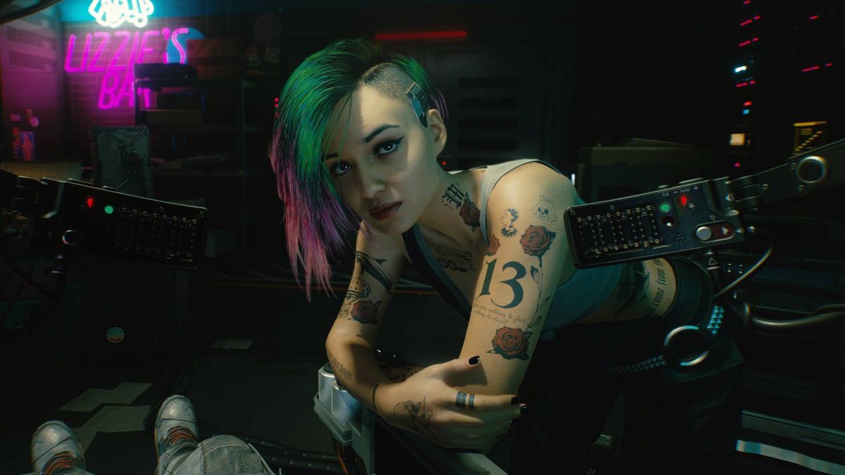 Judy in Cyberpunk 2077, one of V&#039;s romance options, bending down and looking at V in a chair.