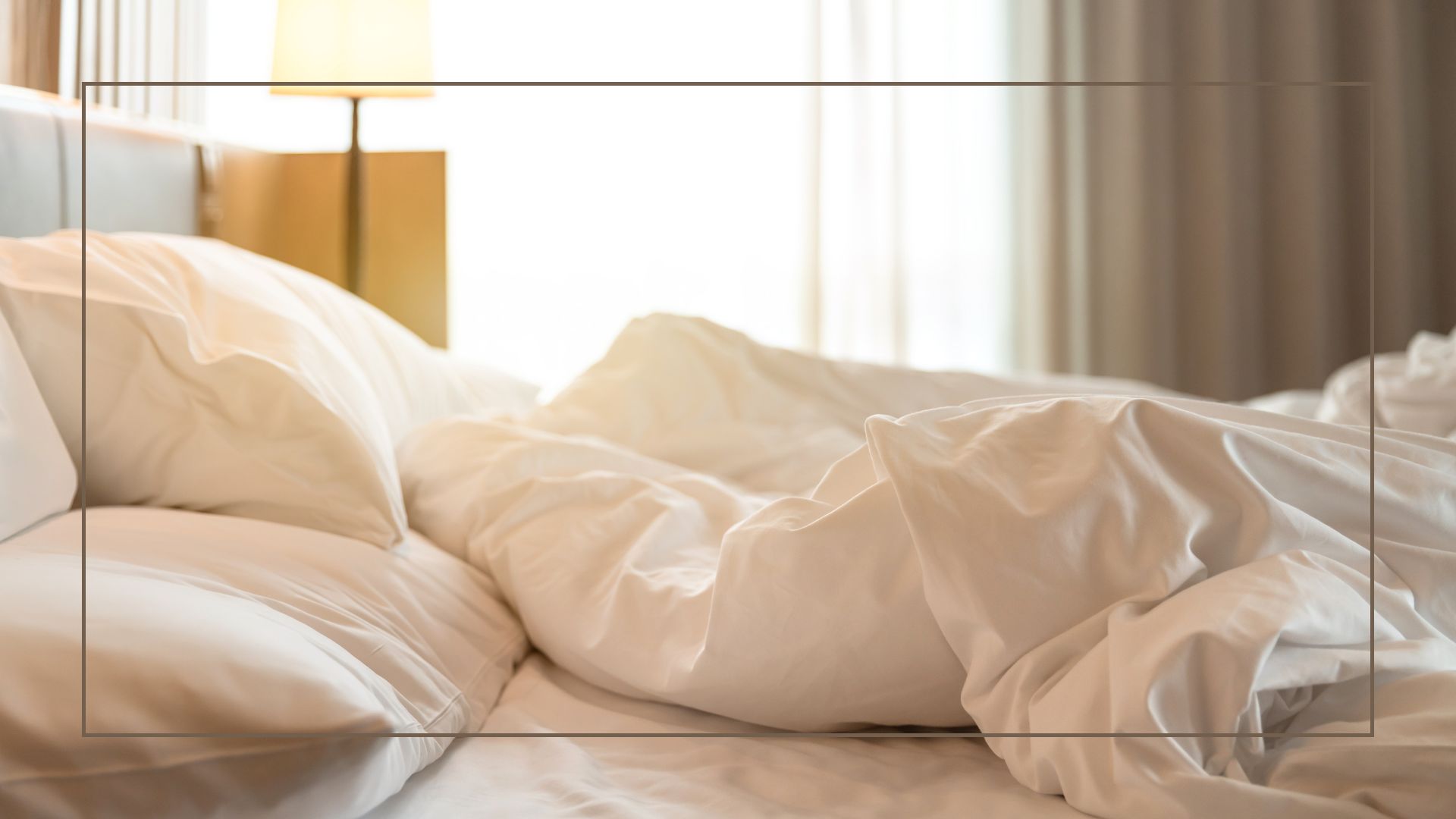  picture of unmade bed with white bedding on in room with lamp