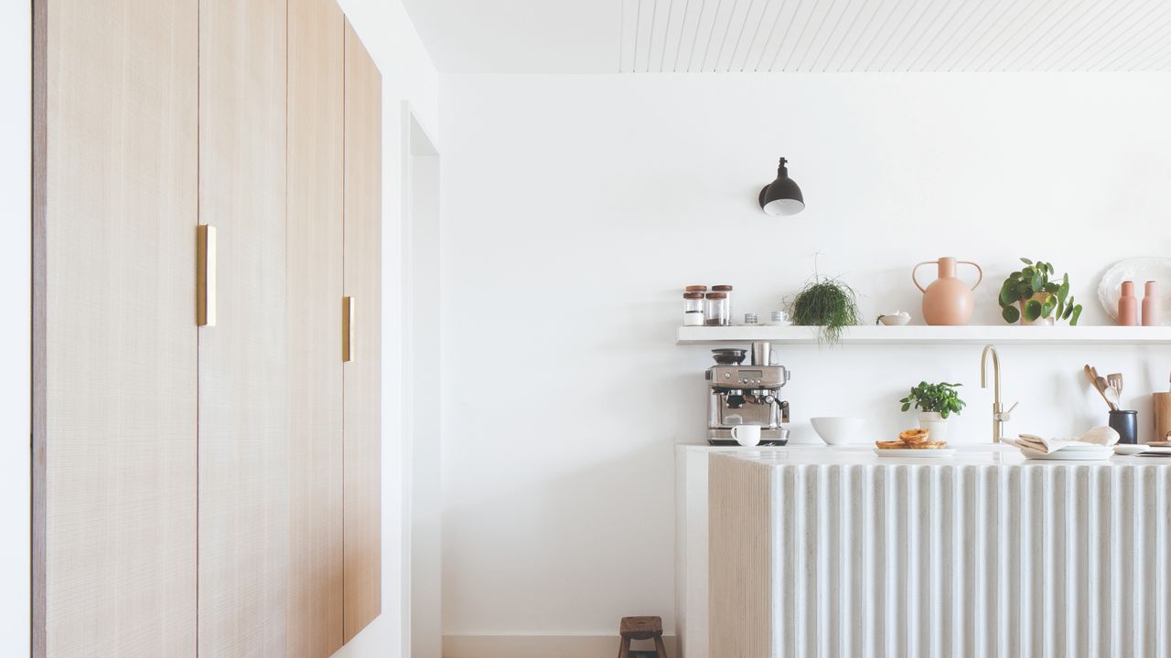 White fluted kitchen island, built in wooden cabinets