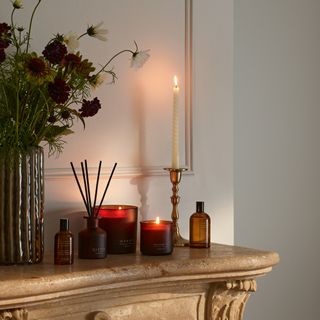 marble mantel lined with lit candles and reed diffuser