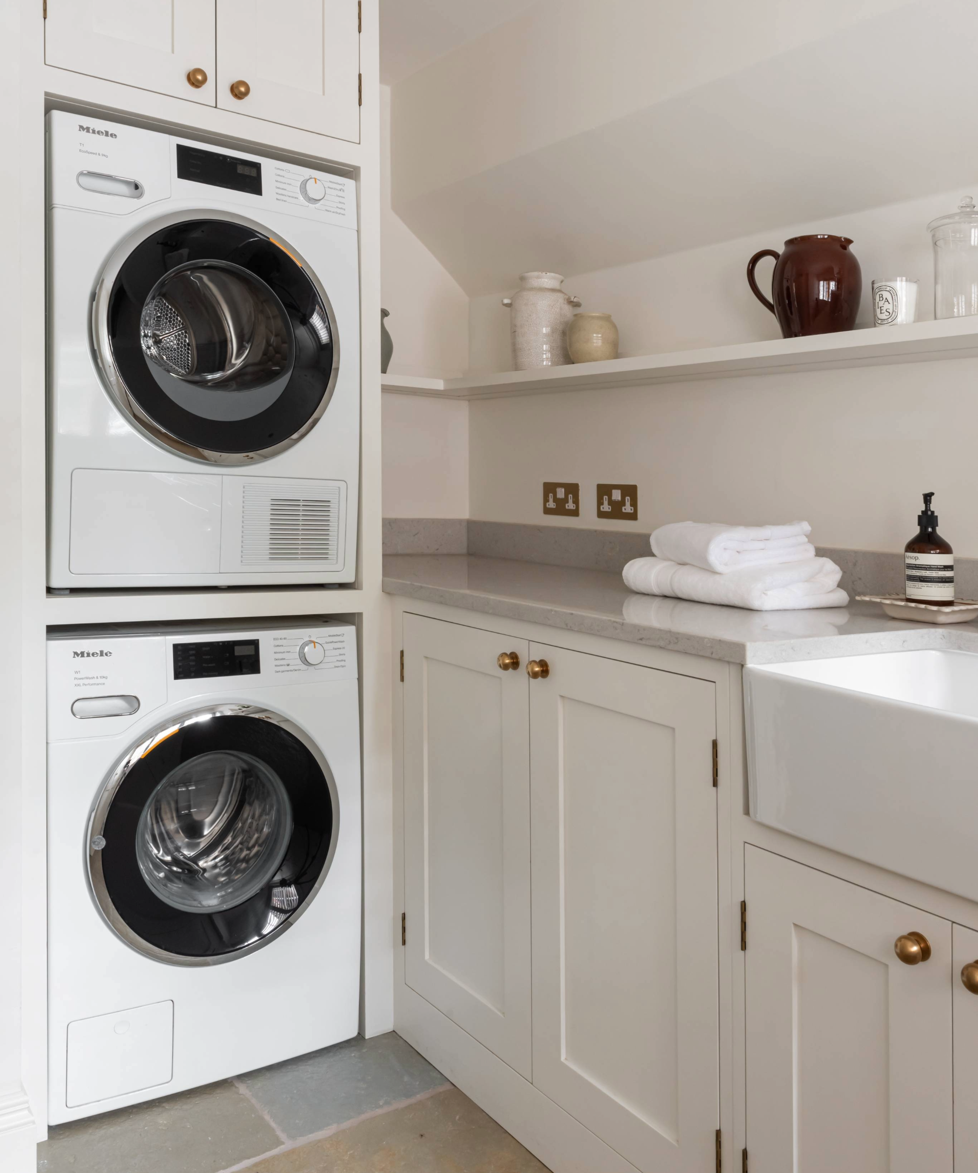 Utility room with towels folded on worktop next to tumble dryer and washing machine