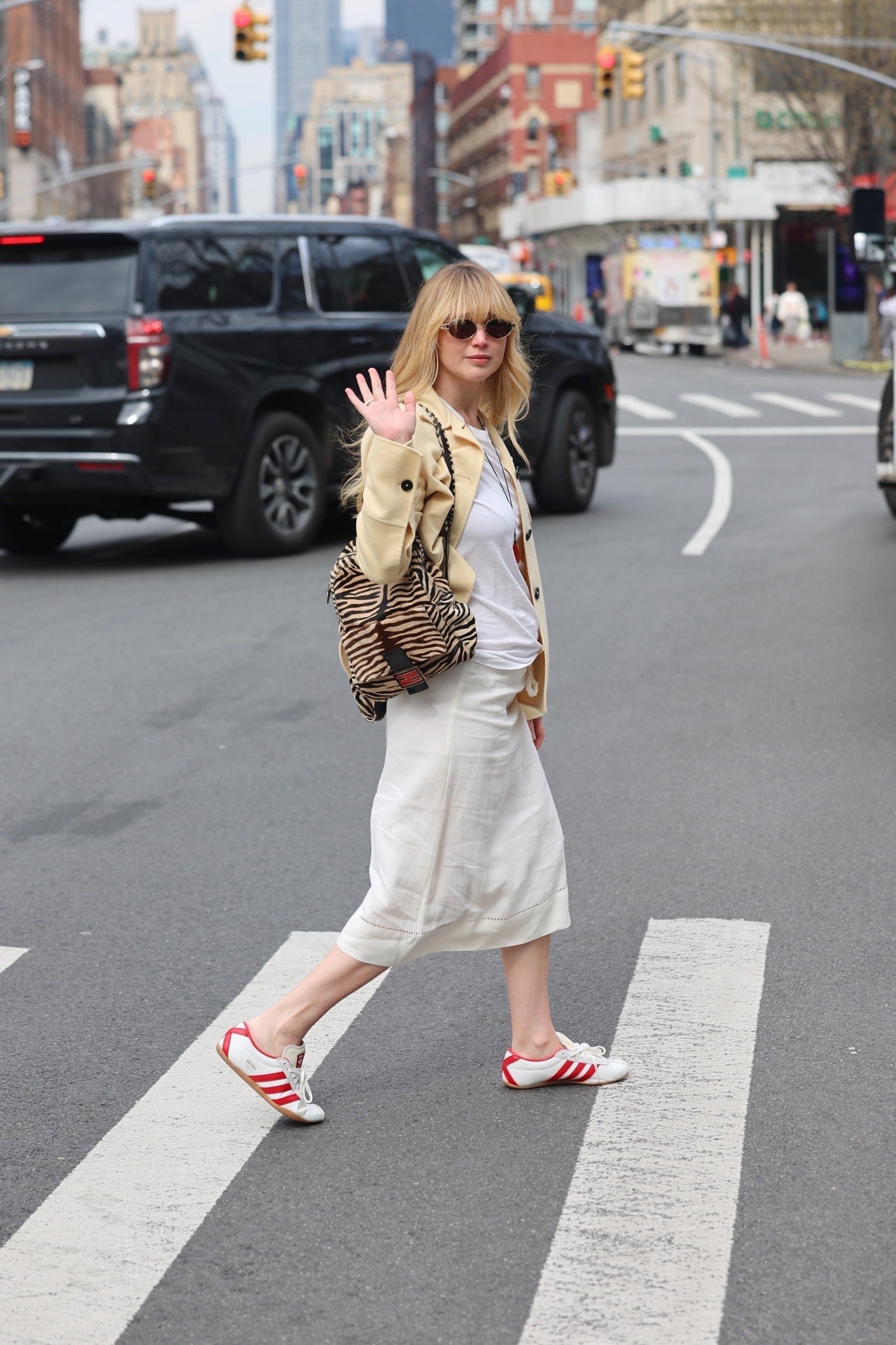 An image of Jennifer Lawrence wearing a yellow shacket, leopard-print backpack, white t-shirt, white skirt and Adidas Tokyo trainers while out in New York.
