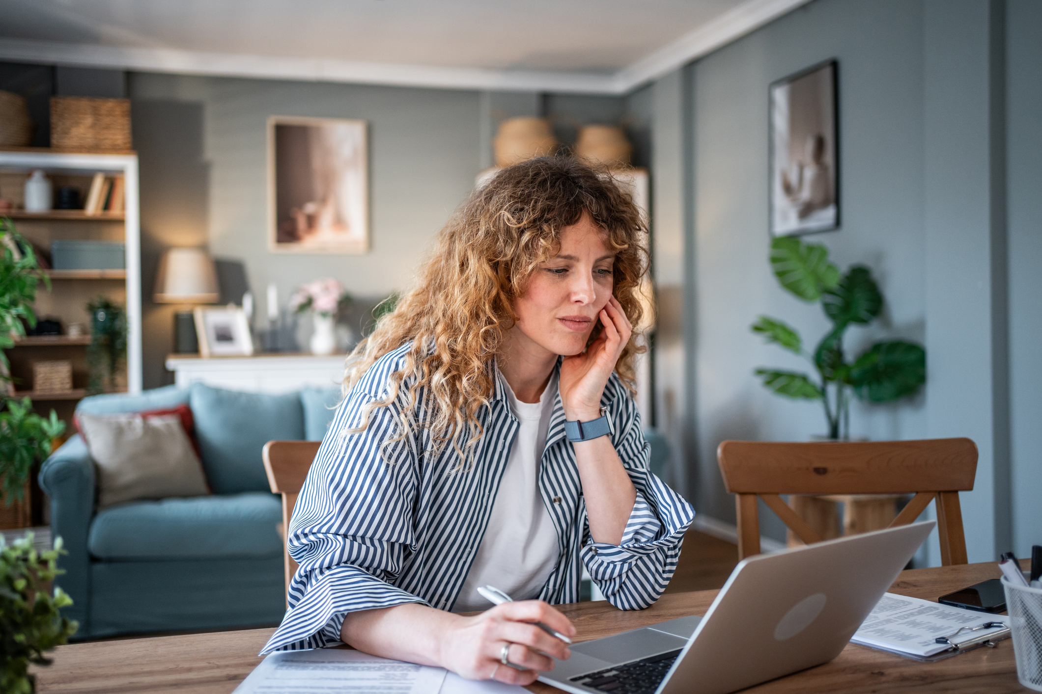 A woman doing research on her laptop sitting at a table.