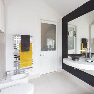 white bathroom with steel towel rack and black washbasin