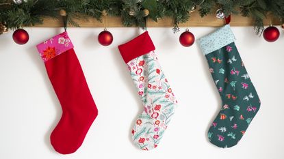 Three festive stockings hanging on a mantel demonstrating how to make Christmas stockings at home