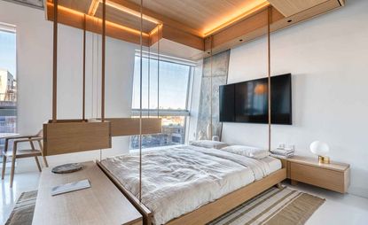 在纽约市的微笑公寓内部，大黄蜂空间的模块化家具。照片上的储物箱从天花板上垂下来，围绕着木床
