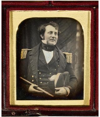 A black and white photo in a frame. It shows James Fitzjames in a Royal Navy uniform.