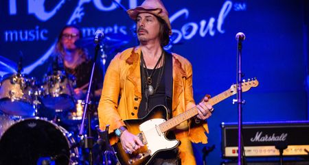 Richie Kotzen plays his Telecaster on a stage backlit in blue