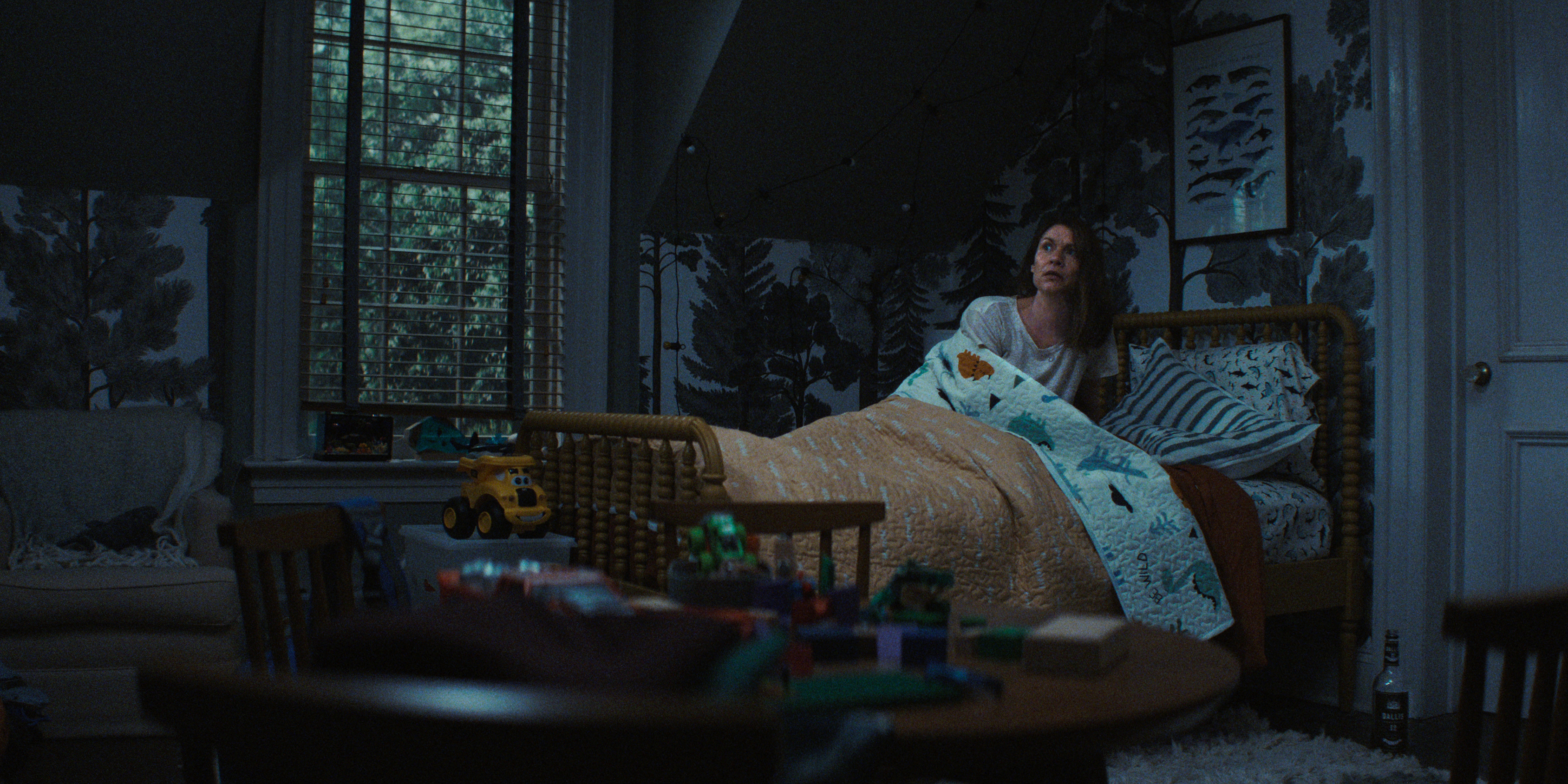 Claire Danes as Aggie Wiggs sleeping in a twin bed in her deceased son's dark bedroom in a still from the netflix thriller the beast in me