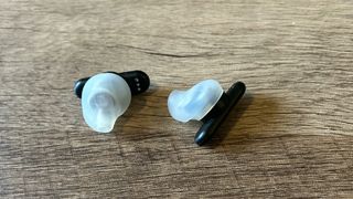 Logitech G Fits earbuds on a wooden table, arranged to show translucent rubber ear tips