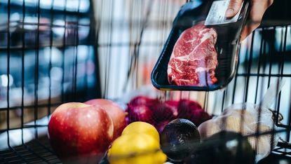 Grocery basket with apples, steak and fruit in it