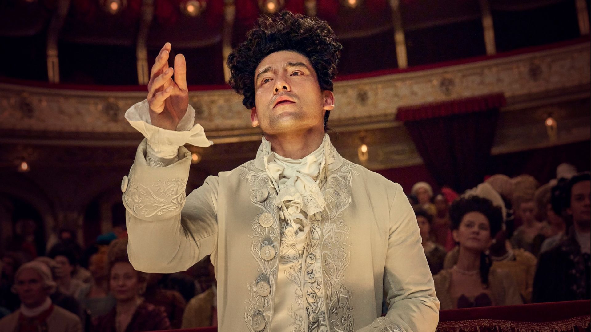 an image of actor will sharpe playing mozart in new SKY series. He is mid conducting in a music hall