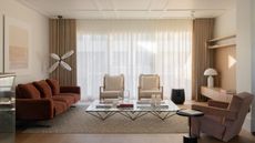 A white and beige living room with curtains over the back window wall, a red sofa, white accent chairs, a pink side chair, and a large glass coffee table.