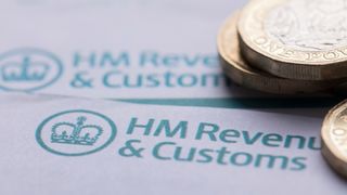 Pound coins stacked on top of two forms from HMRC