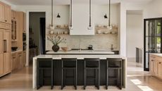 An airy kitchen with an island, pendant lighting, open shelving and a neutral color palette