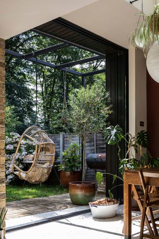 a view out of external pocket doors to a garden with a hanging rattan egg chair