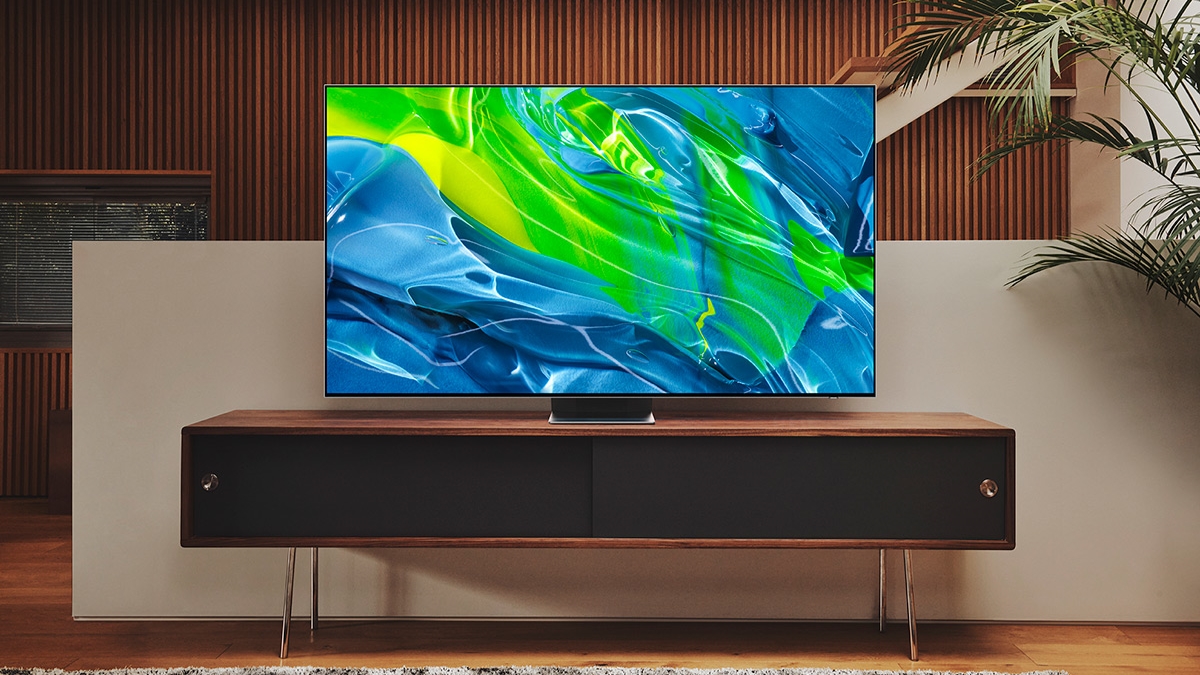 The Samsung S95B OLED TV on a TV stand displaying an abstract blue and green pattern