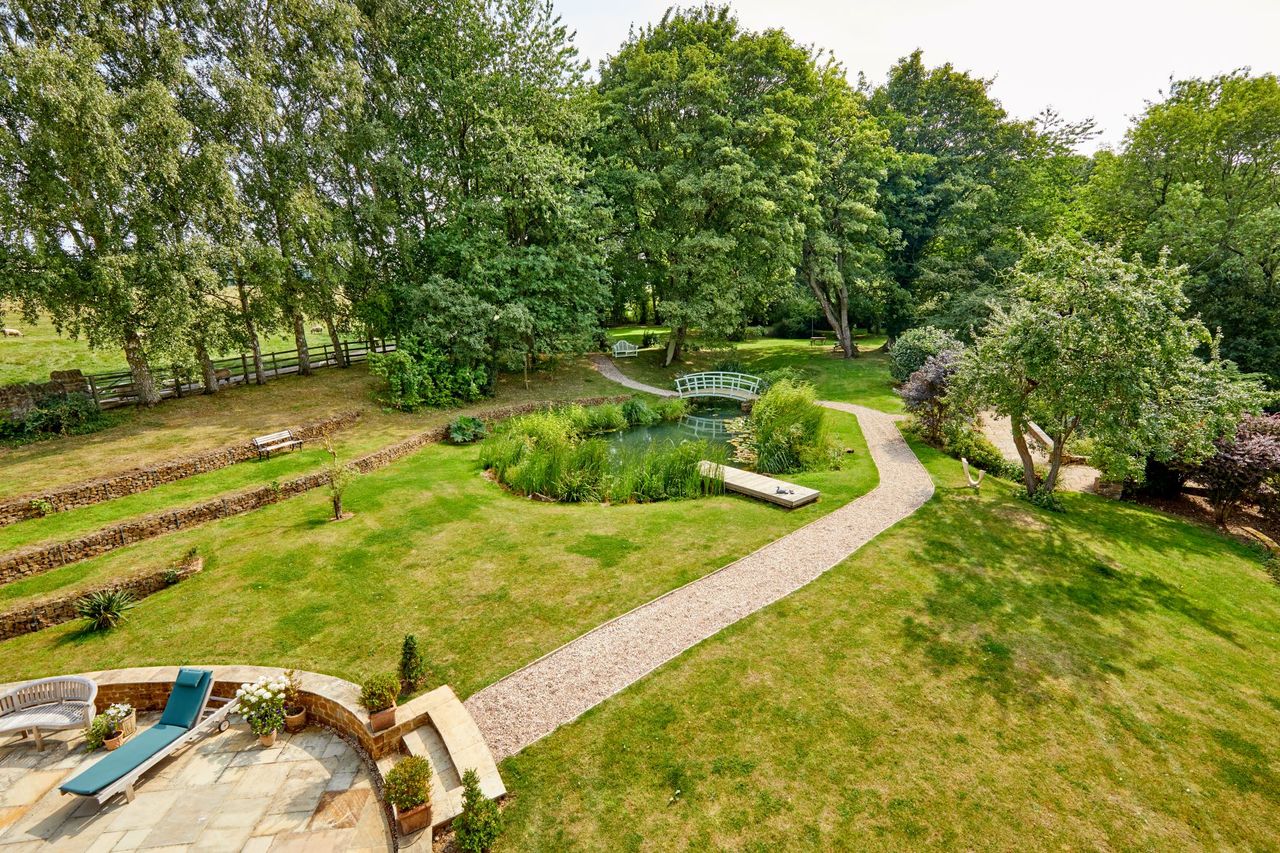 Overhead view of the rear garden which shows the wild pond and garden pathway which leads around the property's boundaries