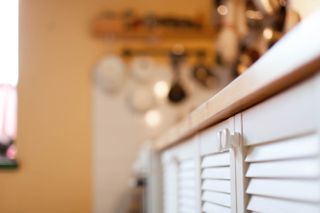 A close up of a kitchen with white shutter cabinets