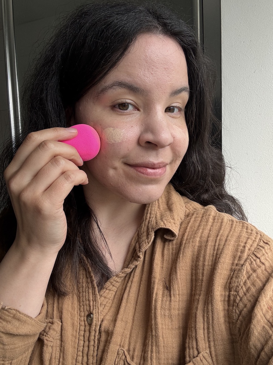 Mica Ricketts applying sheer base with a beautyblender