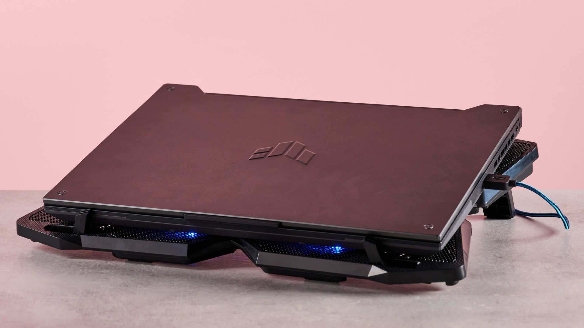 The Klim Wind with a closed Acer Predator Helios 300 sat on top of it in front of a pink background.