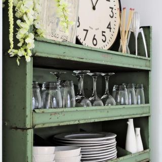 open storage with wine glasses dish and wall clock