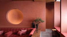 Living room with earthy red walls, sunken seating area with red sofa, and deep walnut woodwork and ceiling