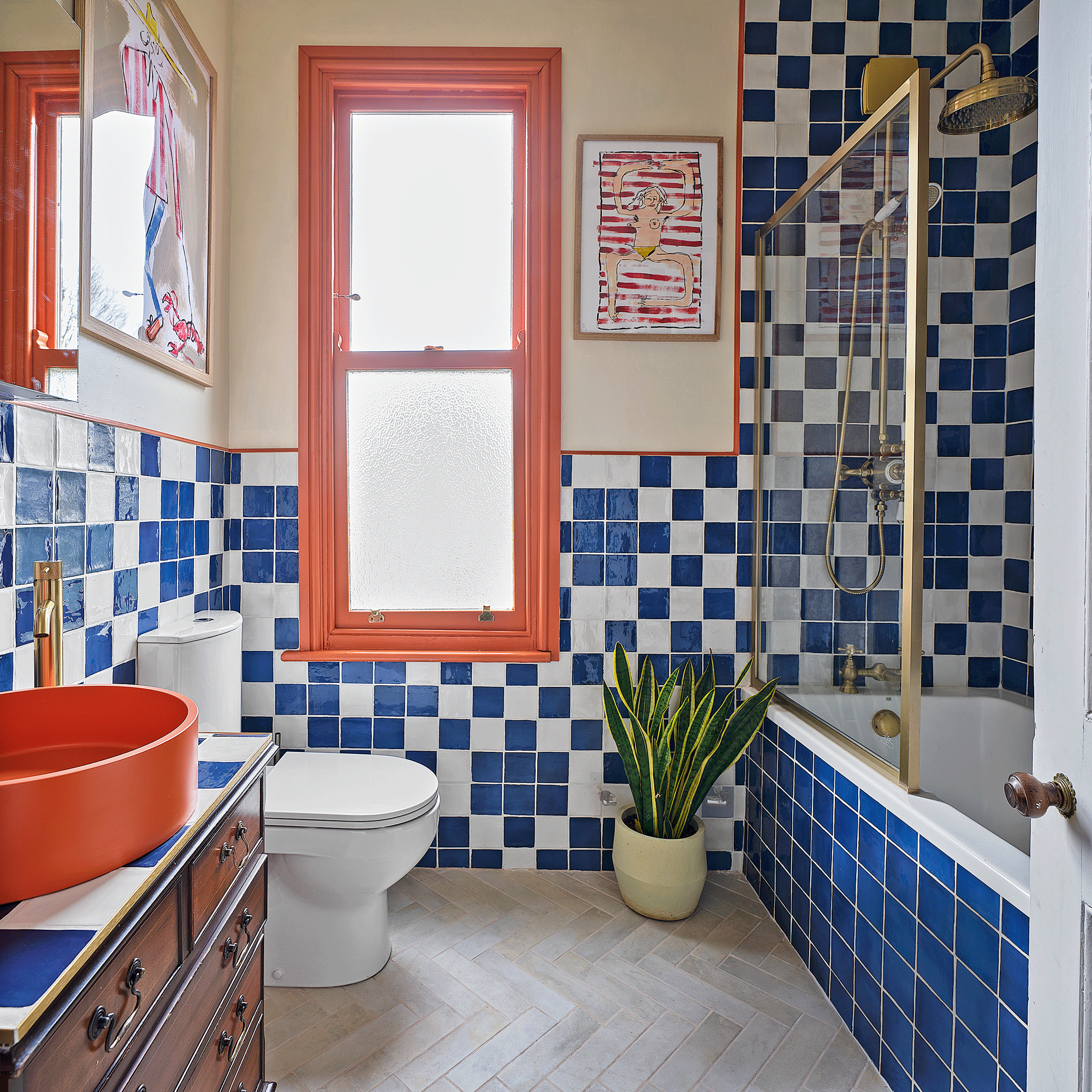 an orange and blue bathroom with blue and white checkered tiles with a shower bath and a glass screen and an orange basin