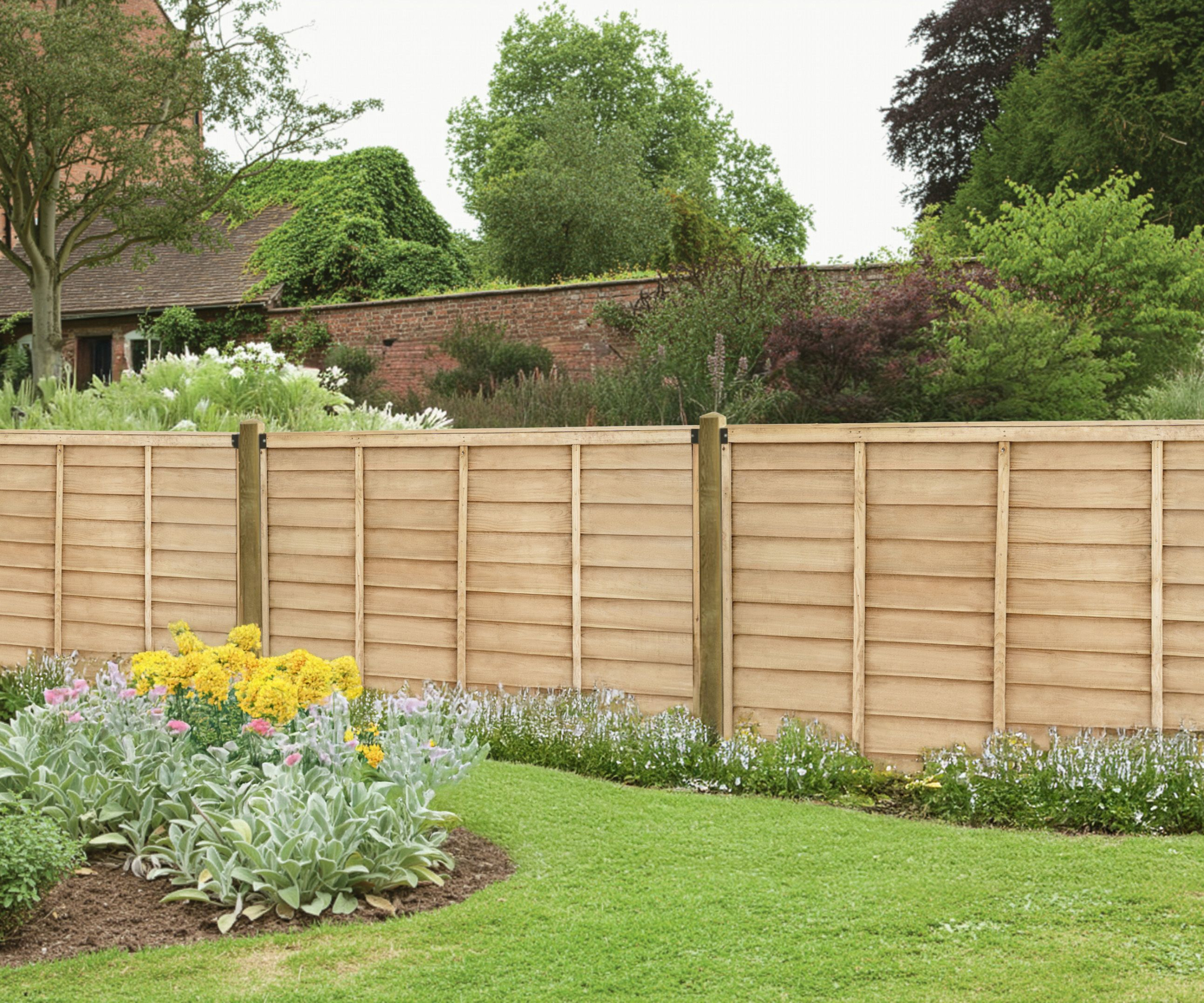 wooden fence running along length of lawned garden with planted borders and house on other side