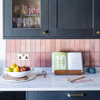 Kitchen with pink tile splashback and dark grey cabinetry