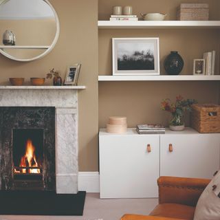 A beige-painted living room with a fireplace and a round mirror above it