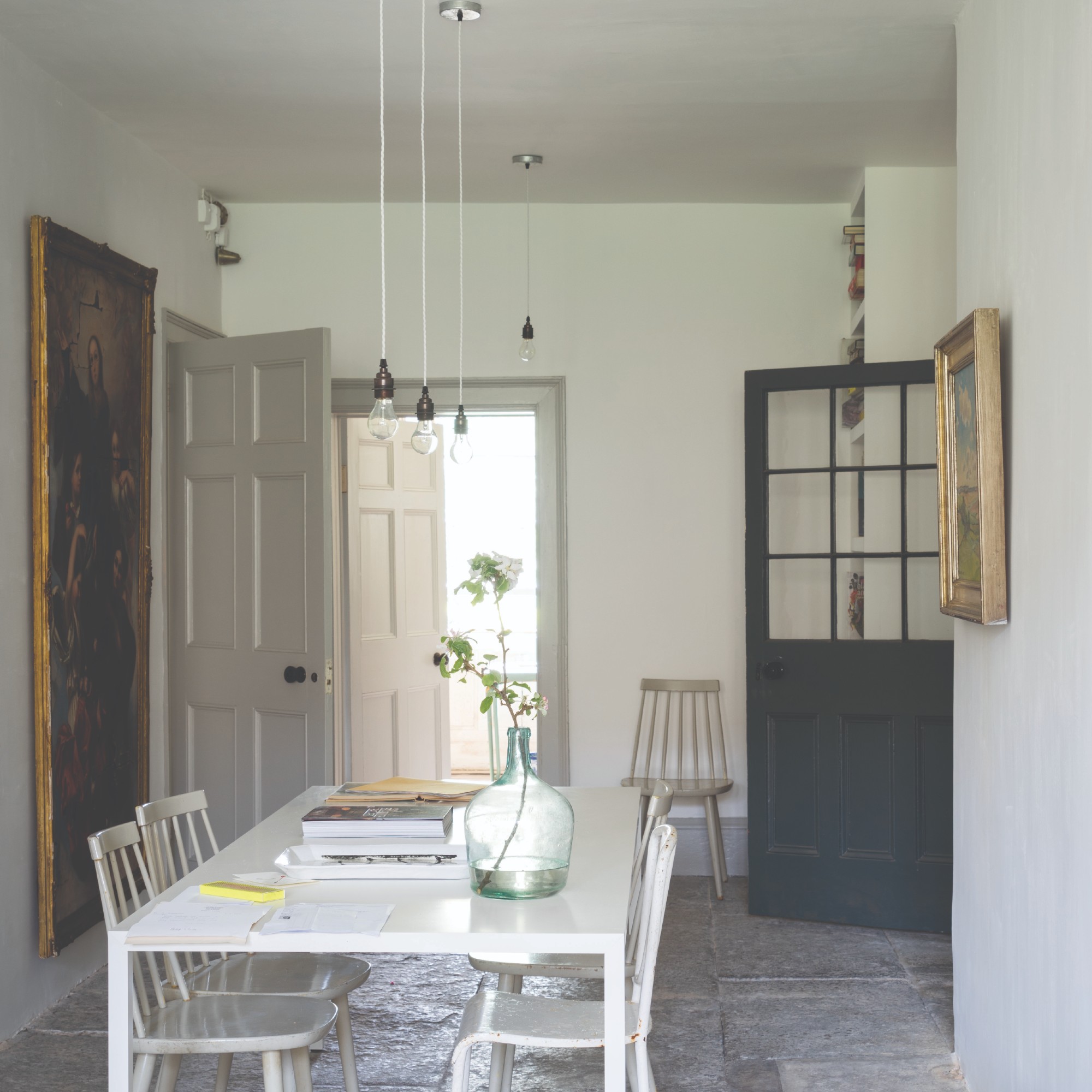 A bright and airy dining room painted in Farrow & Ball's Ammonite with a white table and chairs
