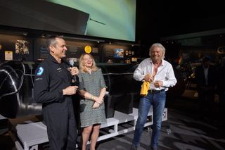 Richard Branson prepares to don a "Future Astronaut Training Program" T-shirt, given to him by Astronaut Mark Stucky (who no longer qualifies as a "future astronaut"), alongside Ellen Stofan, the director of the National Air and Space Museum.