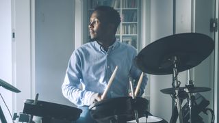 Man in blue shirt plays an electronic drum set