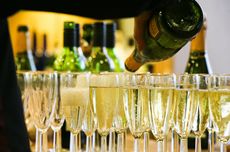 A person pouring from a bottle of sparkling wine into glasses on a bar top best cava under £25