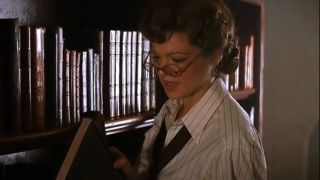 Rachel Weisz studies the spine of a book in the library in The Mummy.