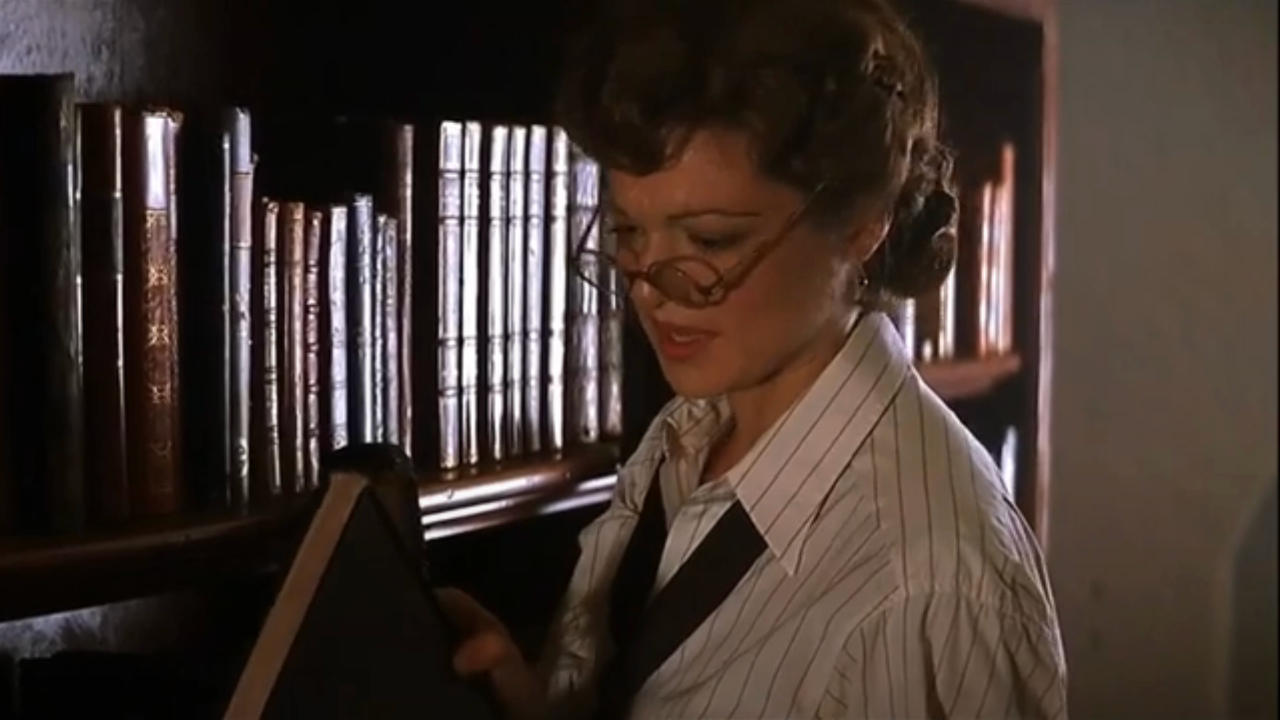 Rachel Weisz studies the spine of a book in the library in The Mummy.