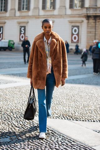 woman wearing short teddy coat, jeans, and sneakers