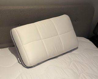 Pillow on a mattress on Louises bed with grey headboard