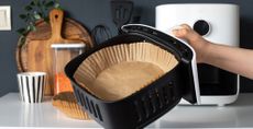 Air fryer basket with a liner in a kitchen to highlight common air fryer mistakes