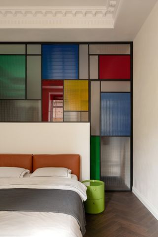 Bedroom with multicolored stained glass screen behind headboard