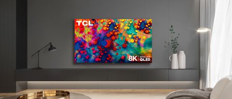 The TCL 6-Series 8K TV in a living room on a TV stand displaying vibrant colors.