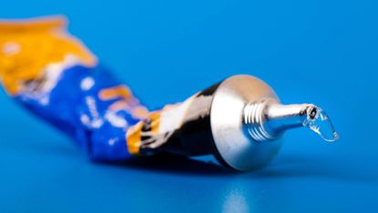 Closeup of squeezed tube of superglue on blue background