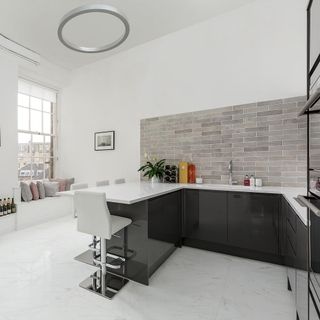 kitchen with grey brick tile and white wall black cabinet white counter and white chair